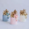 A trio of modern buttercream cakes in pastel blue, pink, and cream, each topped with a stunning fancy faux floral arrangement of gilded palm spears and macarons.