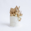 Modern buttercream cakes in cream colour, topped with a stunning fancy faux floral arrangement of gilded palm spears and macarons.